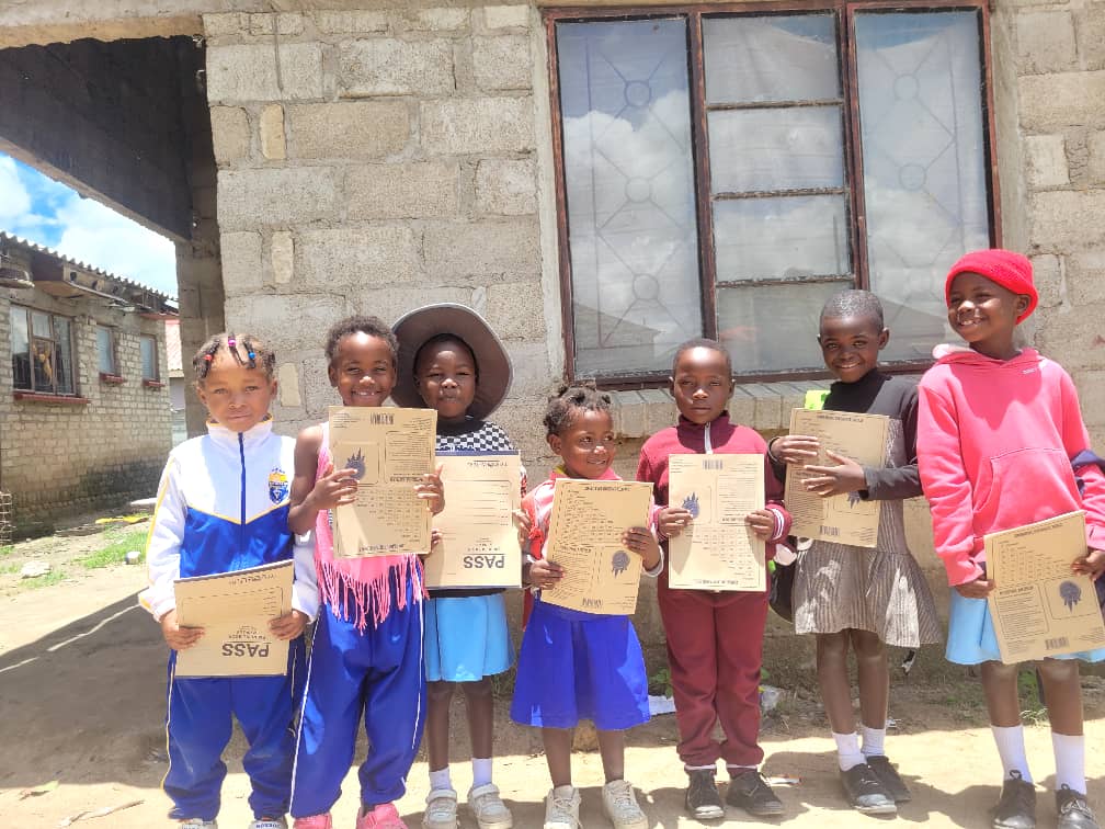 Smiling children from YATT holding their achievement papers